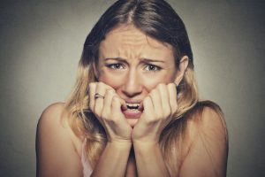 nervous stressed woman biting fingernails looking anxiously